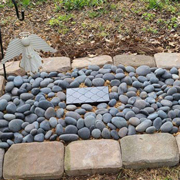 Order 758242 Review Image. Granite headstone for Remington. Headstone nestled among rocks near flowers.