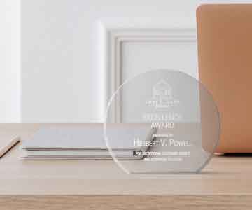 Circle glass Excellence Award displayed on a desk.