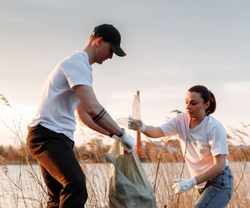 Two volunteers working together to clean trash from beach.
