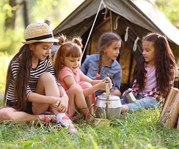 A group of girl scouts playing outside their tent