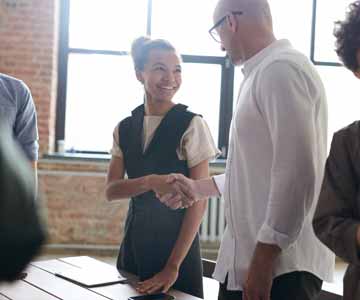 Two people shaking hands in an office boardroom.