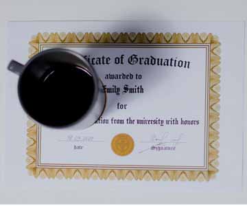 Coffee cup filled with coffee sitting on school diploma