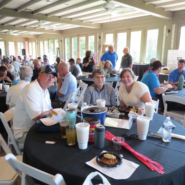 Group Of Event Guests Having Lunch At Round Tables In A Large And Brightly Lit Cafeteria Area With Floor To Ceiling Windows