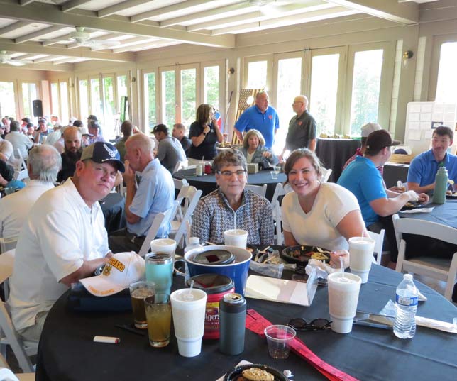Group Of Event Guests Having Lunch At Round Tables In A Large And Brightly Lit Cafeteria Area With Floor To Ceiling Windows