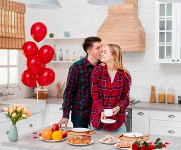 A couple standing in the kitchen with Valentine's Day themed balloons