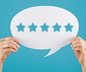 Hands holding up a paper in the shape of a speech bubble with five stars cut out.