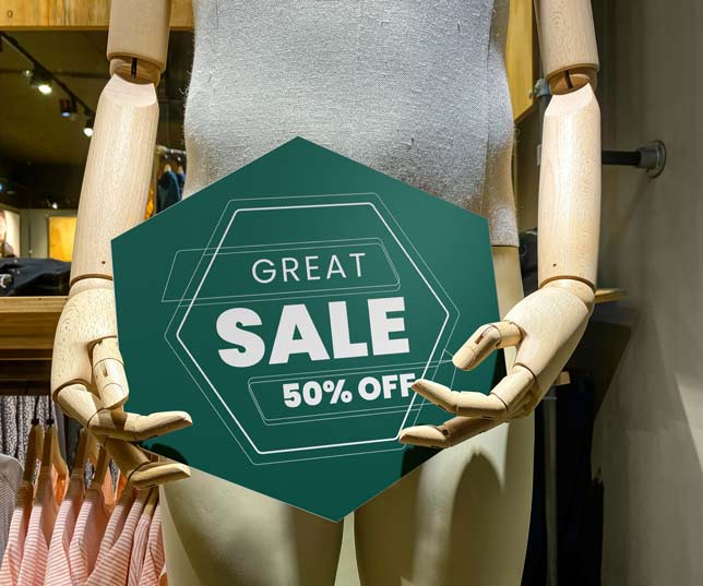 Mannequin In Store Holding A Green Plastic Sign Laser Cut Into Hexagon Shape And Printed With Great Sale Message