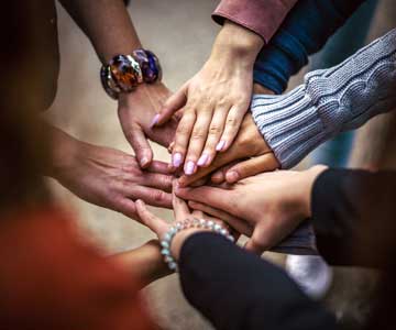 A group of hands coming together in a circle.