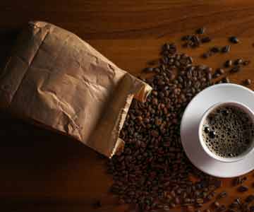 Cup of Coffee Near A Spilled Bag Of Coffee Beans.