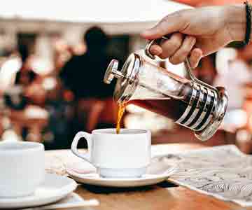 Pouring coffee on a white small cup with a manual brewer.