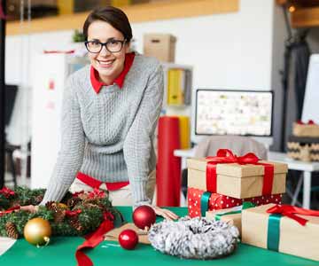 Woman Hands Leaning Onto Table With Christmas Wreath And Wrapped Presents And Holiday Ornaments In Work Office
