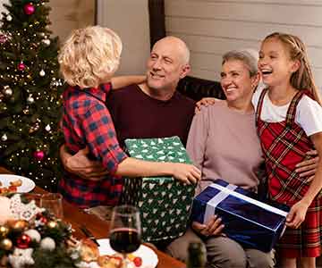 Family sitting happily on a couch next to a Christmas tree, enjoying the festive season together.