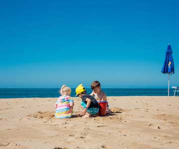 Children sitting in the sand at a beach.