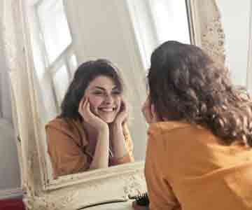 Woman smiling gently at her mirror image