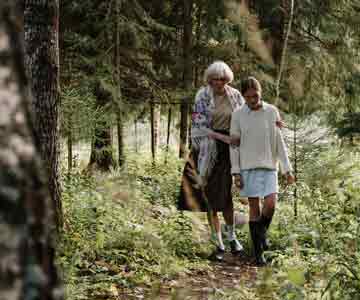 A grandma and her granddaughter stroll through the woods.