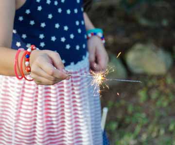 A little girl in an American flag dress, holding a sparkler.