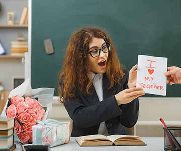 Teacher receiving a white card that says "I love my teacher" along with a bouquet of rose gold roses. 
