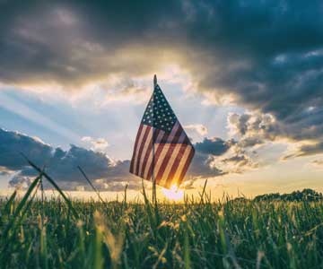 An American flag with a sunset in the background.