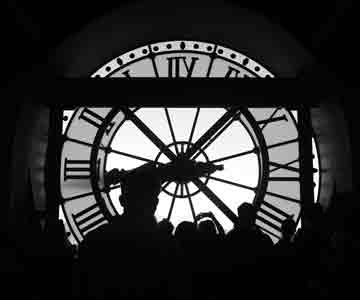 Silhouettes of people standing in front of a giant clock, framed by time.