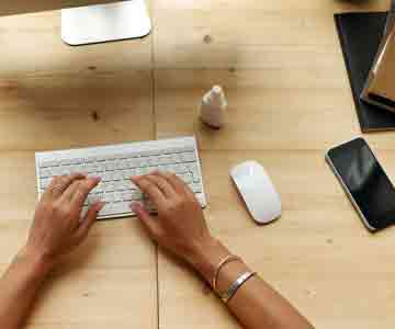 Woman seated on chair, wearing yellow, using computer.