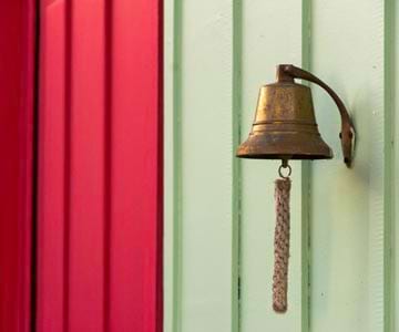 A brass bell hanging on the side of a wall.