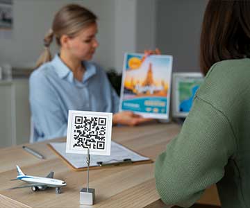 Woman in an office presenting her company's portfolio, with a QR code displayed on her desk.