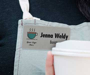 A barista named Jenna Weldy wearing a silver name tag, serving coffee
