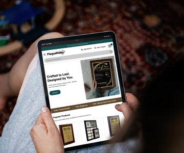 Woman Sitting Indoors And Using Tablet In Her Lap To Browse PlaqueMaker Website Home Page Advertising Star Service Award