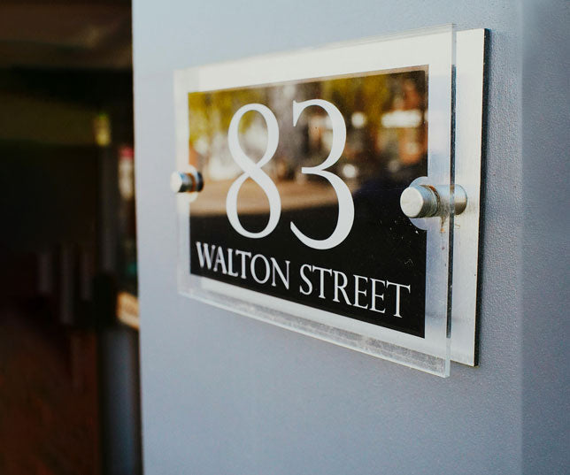 Custom Acrylic Sign Printed With 83 Walton Street Address Text Mounted Onto Column Via Silver Standoffs And Cafe Reflection