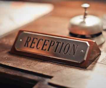 A desk wedge sitting on a wooden surface with Reception written on plate.