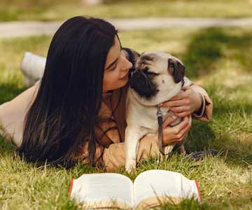 Woman Hugging Her Pet Pug On Grass