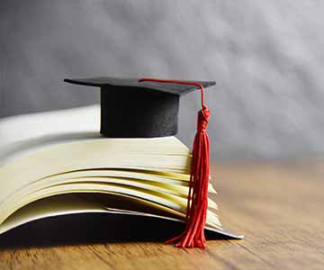 Tiny Graduation Cap Balanced On An Open Book.