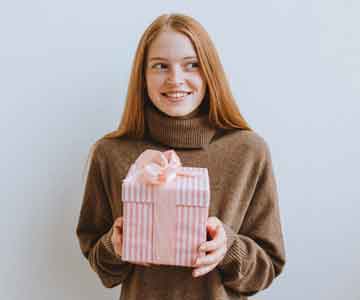 Woman smiling while holding a pink gift. 