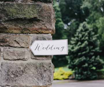 A sign shaped like an arrow with wedding written on the front.