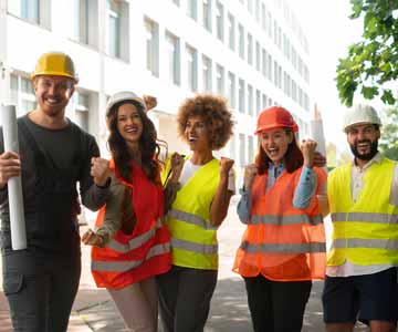 Group Of Volunteers In Construction Attire Standing On Street And Cheering Together