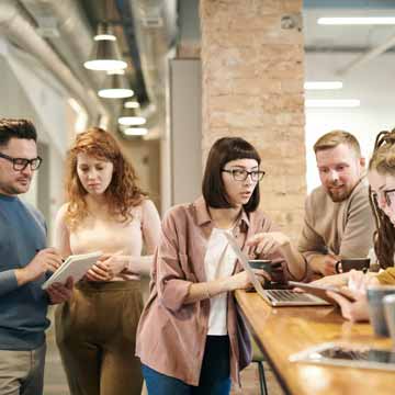 A group of employees talking around a front desk at an office.