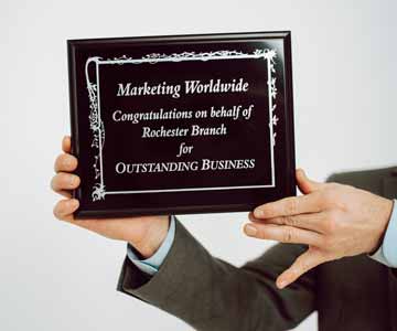 A person holding an engraved plaque for Outstanding Business.