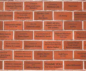 A brick walk way with the bricks engraved with different names.