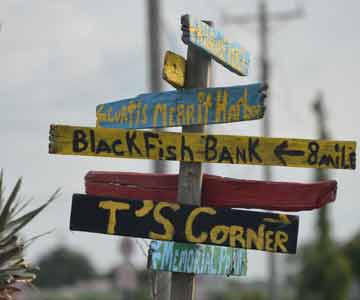 A wooden pole with many hand made signs, pointing in different directions.