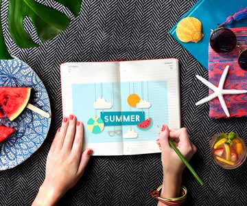 Woman writing in notebook with fruit and summer decor