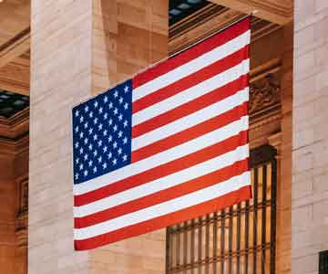 American flag displayed between two large pillars in a hall. 