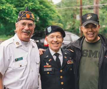 Three happy elderly veterans smiling warmly.