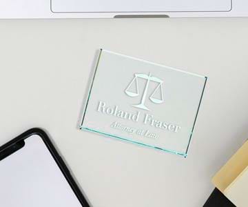A glass jade paperweight lays on desk next to a cell phone and notebook.