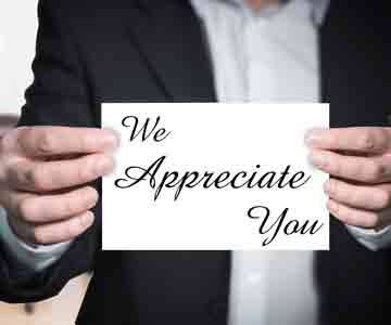 Man holding a small triangle-shaped sign that says “We Appreciate You.”