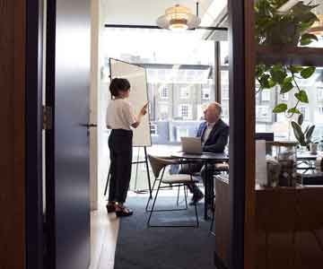 Woman talking to her boss beside a whiteboard.