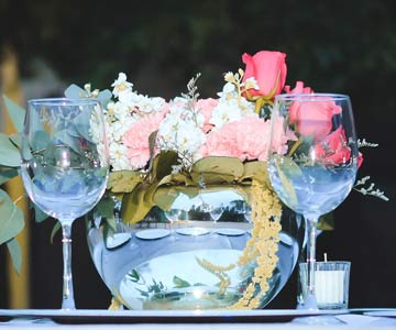 Wine glasses sitting on table with a flower arrangement in the background