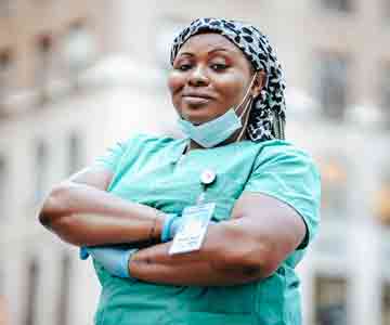 Nurse smiles proudly in her uniform and name tag.