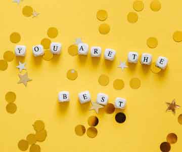 Small dice spelling "You are the best" on a yellow desk.