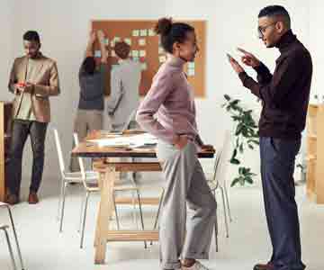 Employees discussing, with busy office behind.
