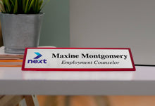 Rosewood Desk Wedge Name Plate With Silver Metal On Desk Near Plant.
